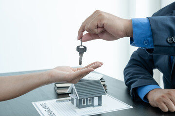 Real estate agent broker hand over the house key to the new owner after completing the signing...