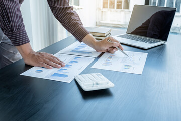 The hands of a male businessman are analyzing and calculating the annual income and expenses in a financial graph that shows results To summarize balances overall in office