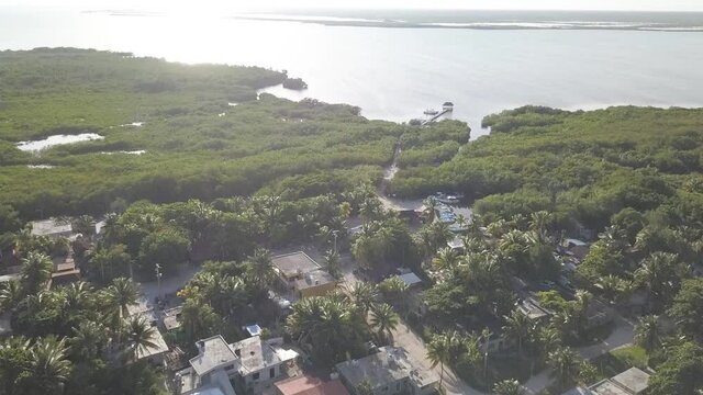 Drone Aerial Fly Over Footage overlooking coastal houses at Punta Allen, Mexico looking out into ocean reflecting sunlight