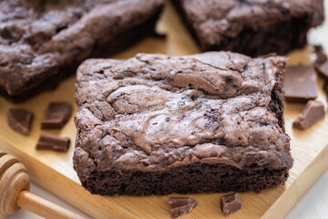 Top view of chocolate brownies on wooden board on white table, homemade sweet and dessert concept
