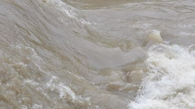 Current section of a muddy highwater river in slow motion
