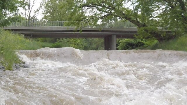 Slow motion of a highwater river with a bridge ending with close splashes