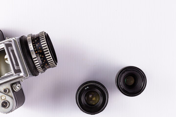 An old camera with interchangeable lenses on a light background.