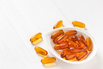 Fish oil capsules on white wooden background