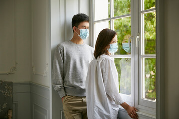 young asian couple in quarantine standing by the window talking