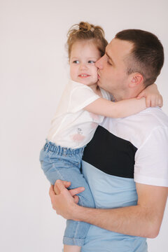 Portrait of little girl with her dad. Cute little daughter with father in studio. Dad kiss daughter in cheek