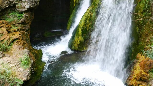 Locked shot of a nice waterfall in a gorge, surrounded by green vegetation.