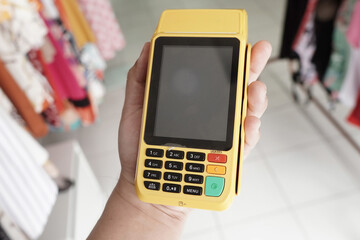 Credit card reader machine. Clothing store environment.