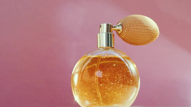 Luxury golden perfume bottle and shining light flares on pink background, glamorous fragrance scent as perfumery product for cosmetic and beauty brand, stock footage