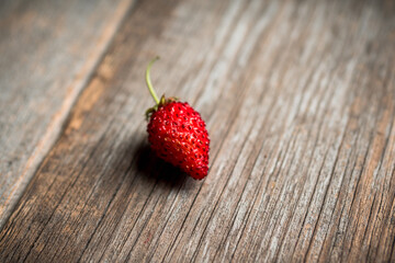 Freshly harvested wild strawberry on the rustic wooden background. Selective focus. Shallow depth of field. 