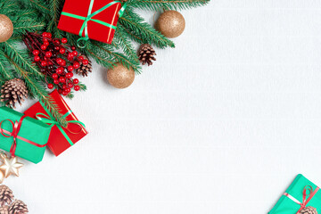 Fototapeta na wymiar Christmas corner with green fir branches, decorations and Christmas gifts on a white background. Background for Christmas and new year cards with a branch of spruce and red berries.
