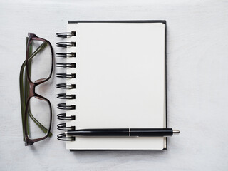 Blank notepad page, pen and glasses. Greeting card. Close-up, view from above, wooden surface. Concept of preparation for a professional holiday. Congratulations for relatives, friends and colleagues