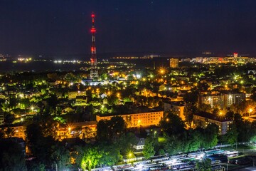 View from roof  of night Ulyanovsk, Russia. High television tower lightened in red in the city center. Bright roads and evening streets and houses..