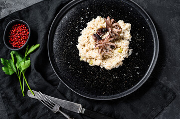 Italian homemade Risotto with octopus and mushrooms, parsley and spices. Black background. Top view