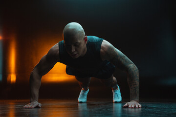 Sportsman doing push ups on the floor in dark studio