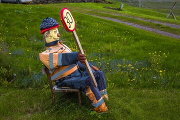 Funny handmade installation of man in road worker uniform sitting on the old chair with road sign.