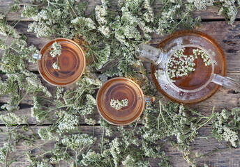 Medicinal herbs.Yarrow herbal tea in a glass teapot with a cup of honey on a wooden natural background. © Татьяна Пинкасевич