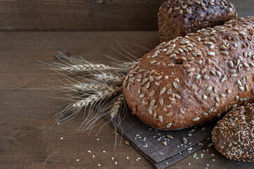 Fresh loaves of bread from the bakery with wheat ears on a wooden background. Copy space.