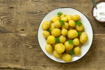 Young boiled potatoes with parsley on a rustic background