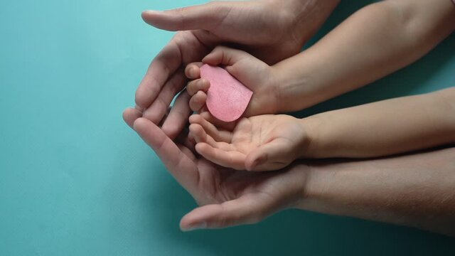 adult and child hands holding red heart,health care. donate and family insurance concept