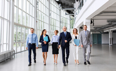 people, work and corporate concept - business team with folders walking along office building and talking