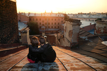 man and woman siting on rooftops historic center St. Petersburg and enjoying with  amazing sunset.