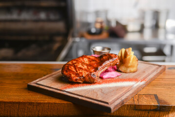 Medium rare grilled Beef steak with roasted potato wedges and green salad on cutting board on wooden background.