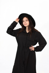 A girl in a black hat poses and smiles on a white background