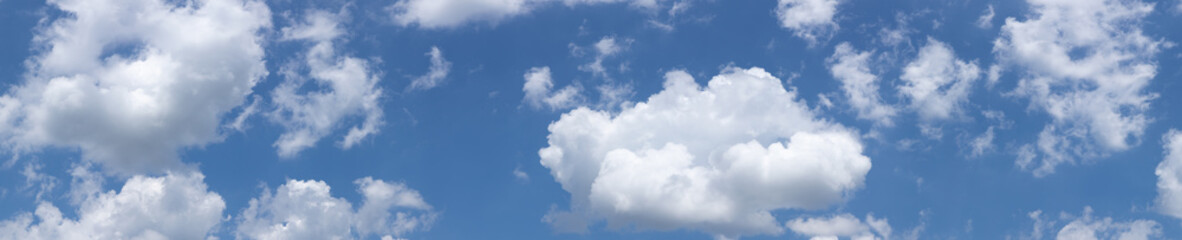 Panorama of diffuse white, puffy clouds against a clear blue sky background, creative copy space,...
