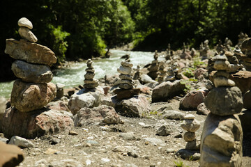 a lot of stone pyramids on the cold stream beach in alps forest