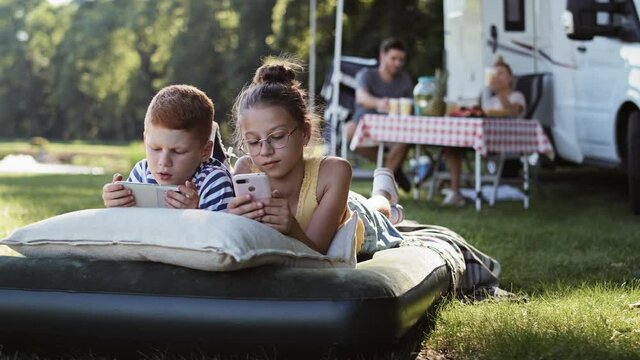 Tracking right video of children with phone on camping holiday. Shot with RED helium camera in 8K.
