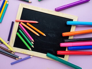 Chalkboard, colored pencils on a purple background. Back to school.