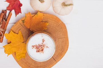 Coffee lattee with cinnamon on wooden tray and autumn leaves
