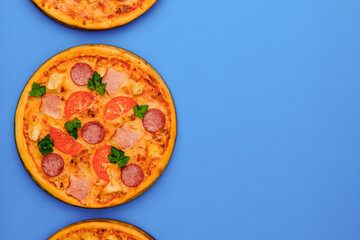 Three pizzas on the blue azure background. Pizza isolated. Banner with copy space for text or logo. Italian cuisine.