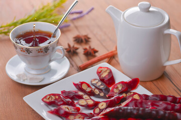 Tasty oriental sweets. Caucasian delicacy churchkhela - georgian nut treats. Served with a glass of tea and a tea pot.
