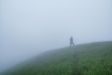 Fototapeta premium Silhouette of a man in dense fog in a mountainous area