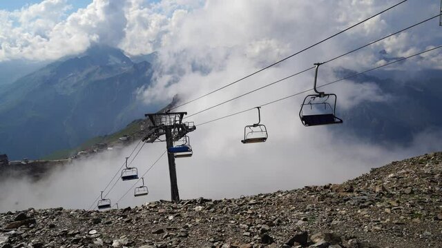 Cableway near smoke in rocky countryside. Modern ropeway located on stony ground near thick fume in amazing mountainous terrain