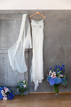 Wedding dress and veil hanging near bouquets