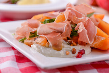 White dish with carpaccio of beef on arugula. Table served for thanksgiving dinner. Autumn food on wooden background.