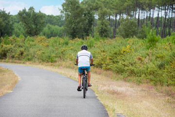 senior riding a bike on the cycle path through the forest