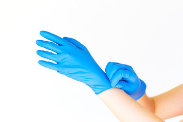 Stock photo of a woman's hands putting on blue latex gloves isolated on white