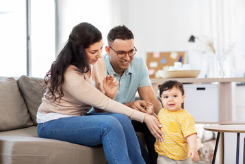 family and people concept - happy mother, father and baby son sitting on sofa at home