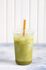 Matcha green tea ice latte with almond milk in a glass. Grey stone background.