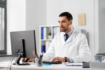 Obraz premium healthcare, medicine and people concept - male doctor with computer working at hospital