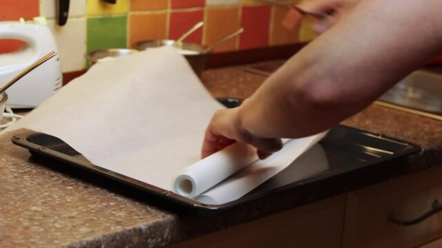 Cutting grease proof paper for a metal baking tray to bake a cake