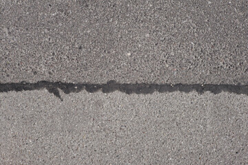 Close up of rough grey asphalt road or bike path, grungy graphic background