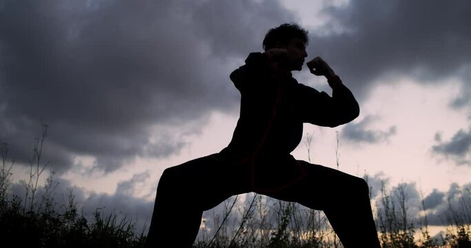 Silhouette of a man practicing martial arts on a sunset. Kung Fu