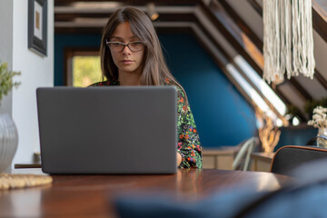 Young business woman sitting in front of portable laptop computer reading email from client.
