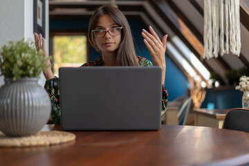 Young business woman explaining, while sitting in front of portable laptop computer.