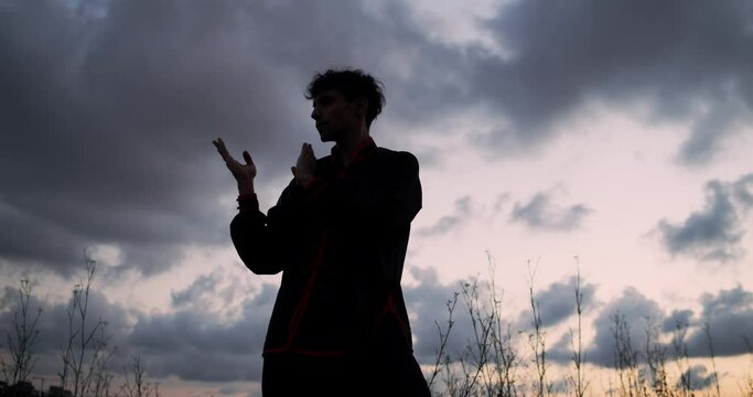 Man practicing chikung during a sunrise on a mountain with Barcelona on the horizon